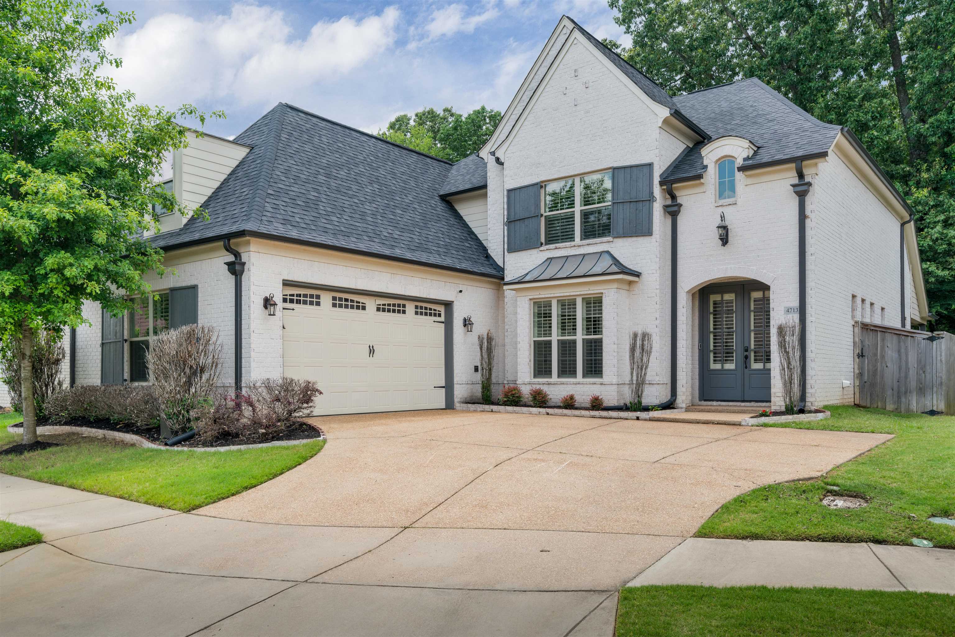 French provincial home with brick siding, a shingled roof, and concrete driveway