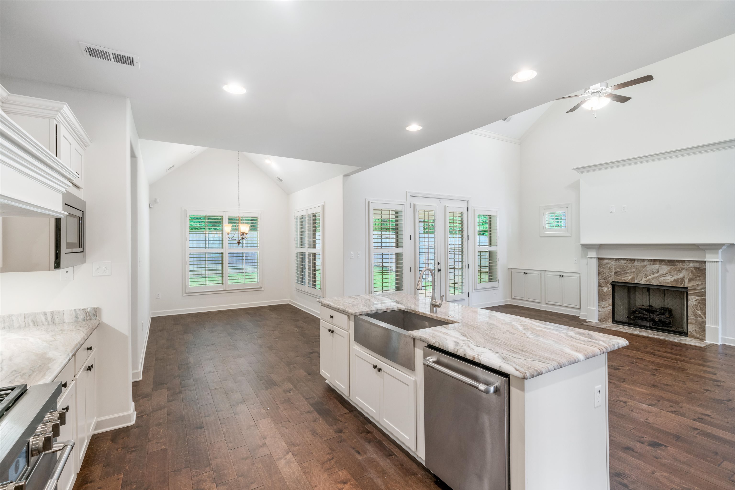 4713 Emmas Circle West Collierville, TN 38017 - Photo 28 of 28 a large white kitchen with granite countertop a stove top oven a sink a refrigerator and white cabinets with wooden floor