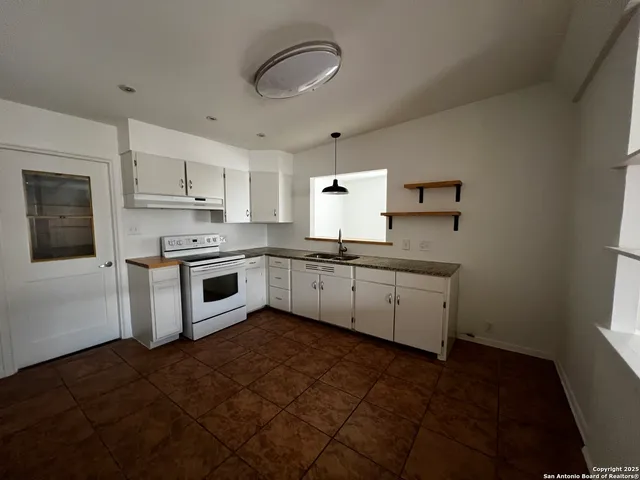 a kitchen with granite countertop white cabinets stainless steel appliances a sink and a window