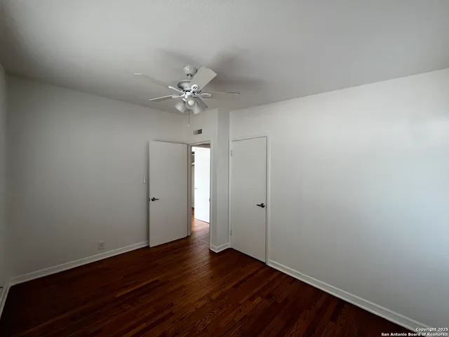 an empty room with wooden floor and fan