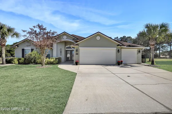 a front view of a house with a garden and trees