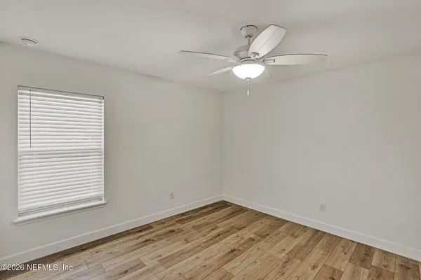 an empty room with a window and ceiling fan