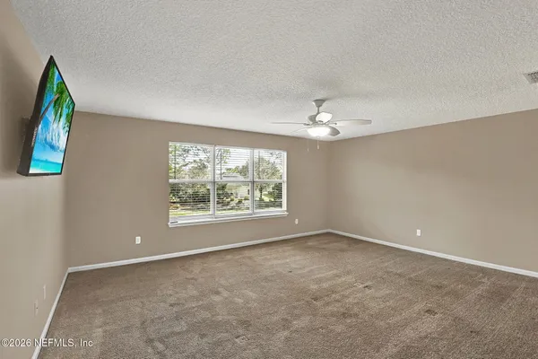 an empty room with windows and chandelier fan