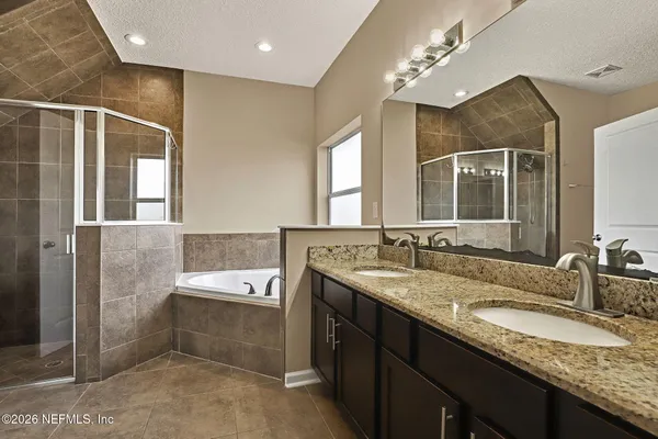 a bathroom with a granite countertop bathtub a double vanity sink and a mirror