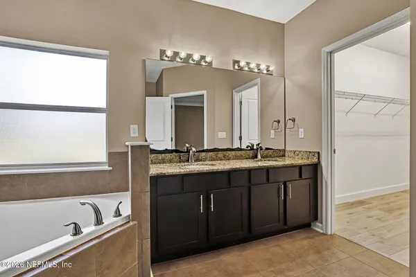 a bathroom with a tub a double vanity sink and mirror
