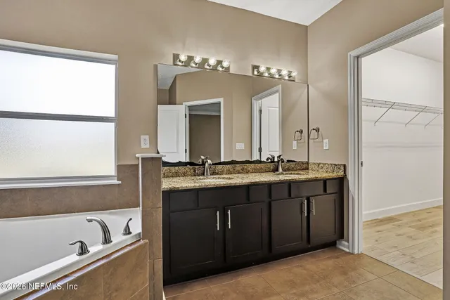 a bathroom with a tub a double vanity sink and mirror