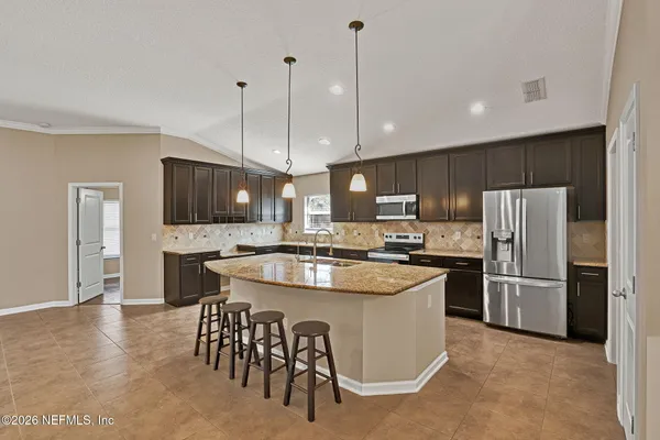 a kitchen with kitchen island a refrigerator stove a sink and a oven