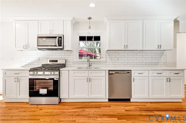 a kitchen with a refrigerator wooden floor and white cabinets