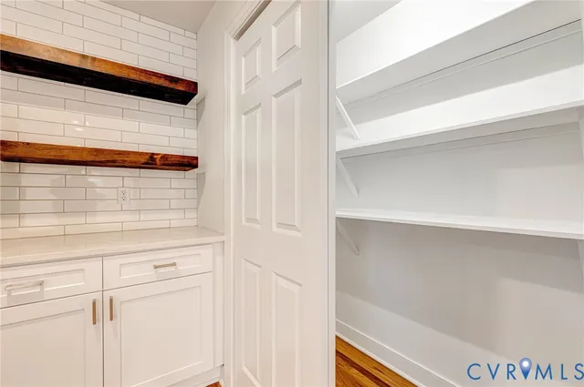 an empty room with wooden floor cabinet and windows