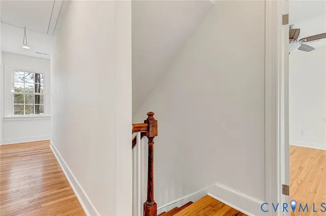 a view of empty room with wooden floor and fan