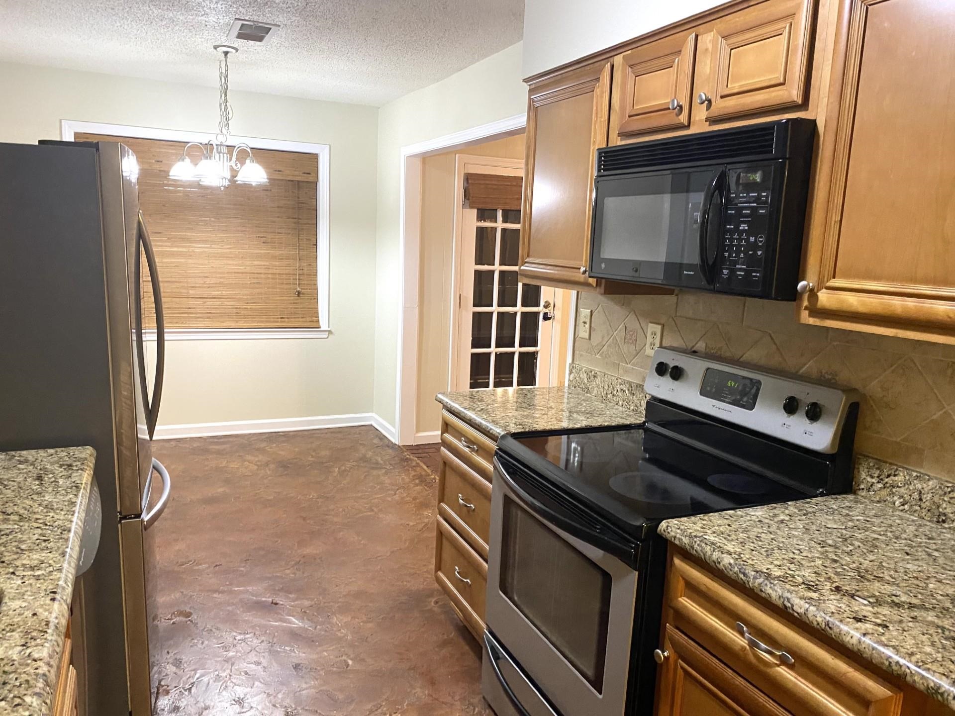 7918 Farmingdale Road Germantown, TN 38138 - Photo 2 of 12 Kitchen with pendant lighting, an inviting chandelier, stainless steel appliances, light stone counters, and decorative backsplash