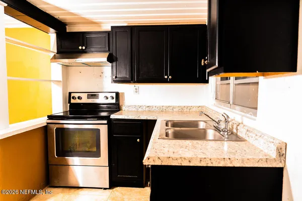 a kitchen with granite countertop a sink stove and microwave