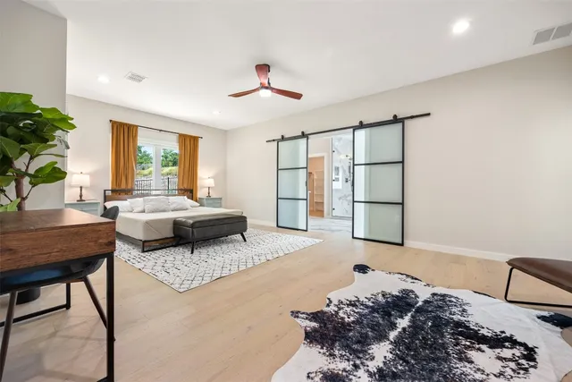 a spacious bedroom with a bed a chandelier and a window
