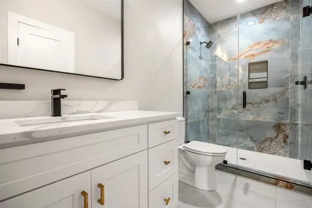 a bathroom with a double vanity sink toilet and shower