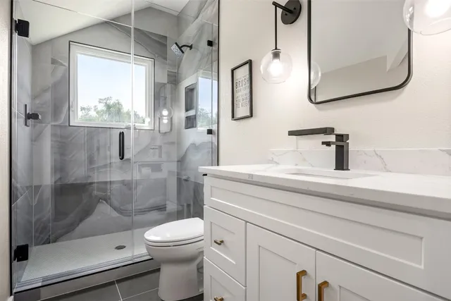 a bathroom with a sink a toilet and shower