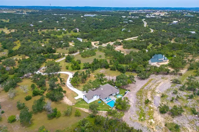 an aerial view of residential houses with outdoor space and trees