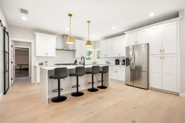a kitchen with stainless steel appliances kitchen island granite countertop a sink refrigerator and cabinets