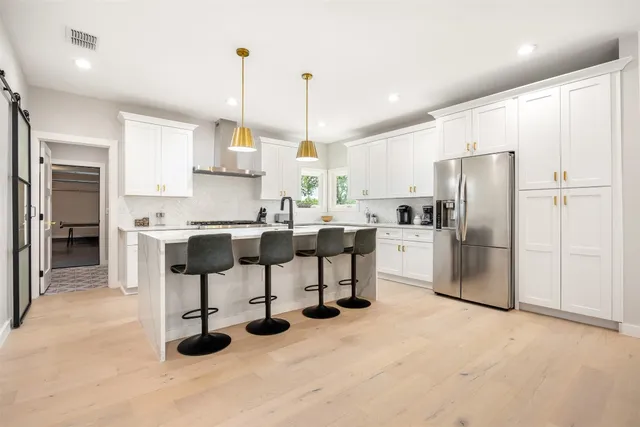 a kitchen with stainless steel appliances kitchen island granite countertop a sink refrigerator and cabinets