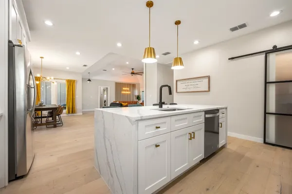 a large kitchen with kitchen island a large counter top a sink a refrigerator and a fireplace