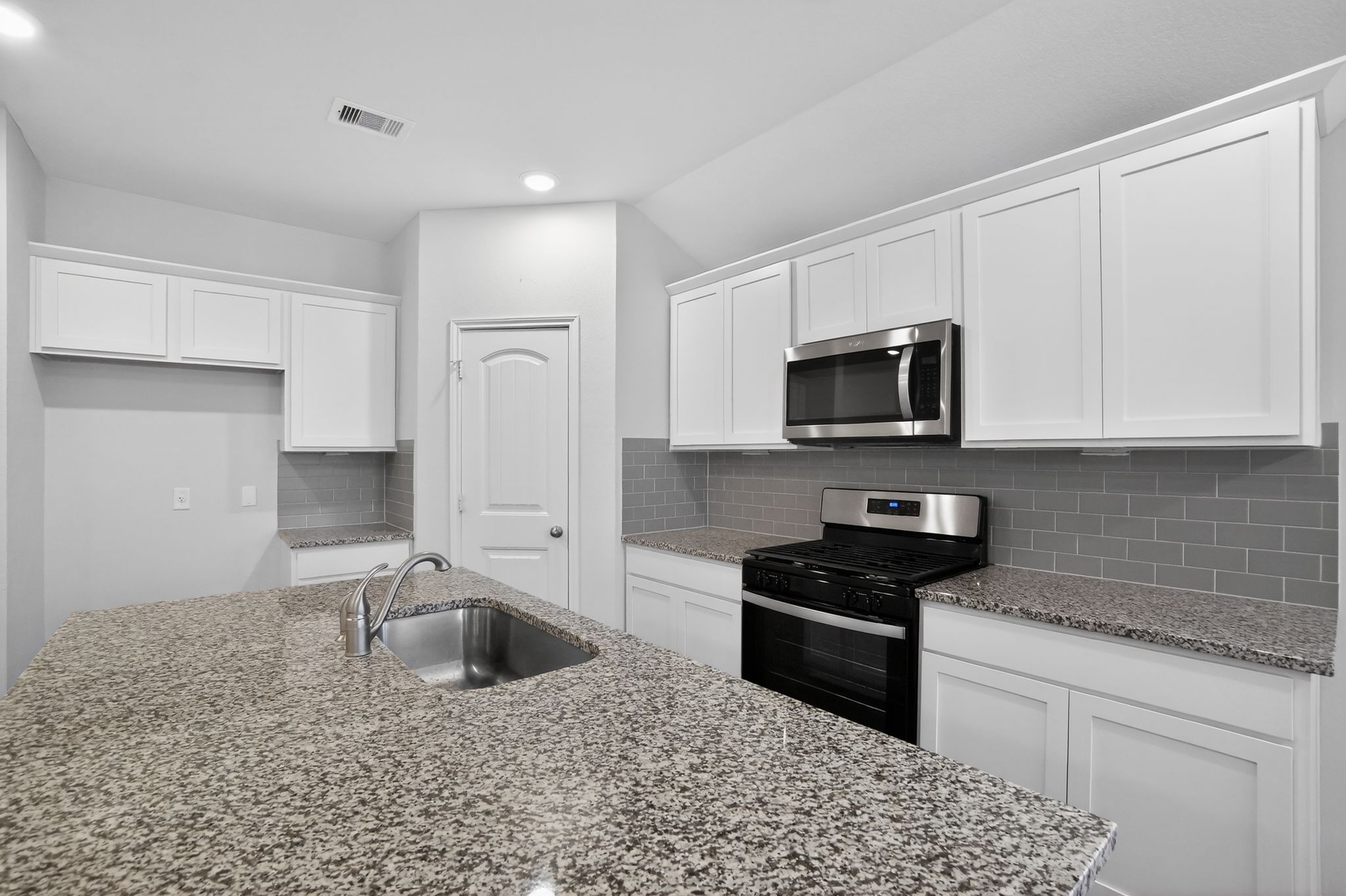206 Addison Place Lockhart, TX 78644 - Photo 5 of 25 a kitchen with granite countertop a sink a stove a microwave and refrigerator