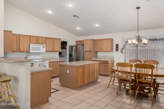 a kitchen with stainless steel appliances granite countertop a table chairs and a refrigerator
