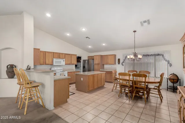 a kitchen with kitchen island a dining table chairs stainless steel appliances and cabinets