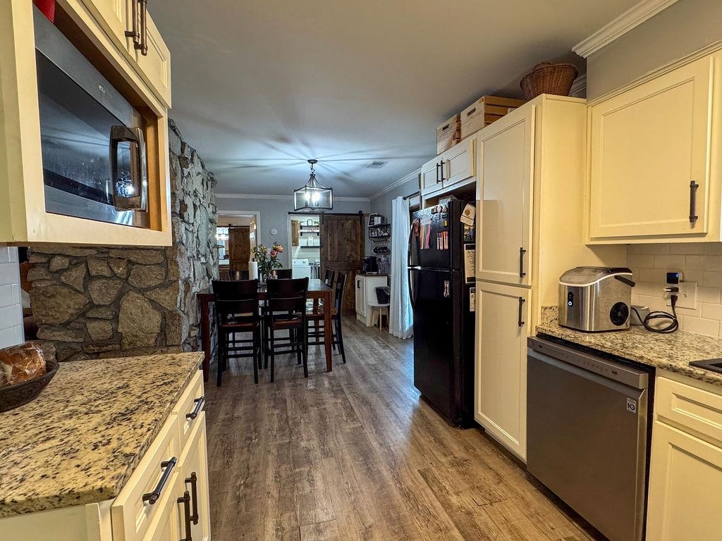 127 Walton Loop Covington, TN 38019 - Photo 11 of 40 a kitchen with granite countertop a refrigerator a stove a dining table and chairs with wooden floor