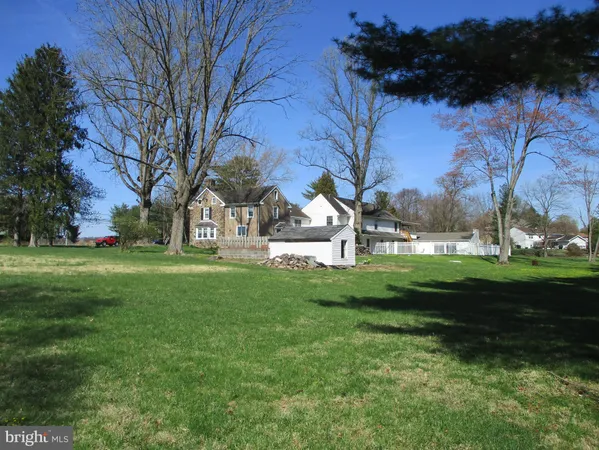 a view of white house with a big yard and large trees
