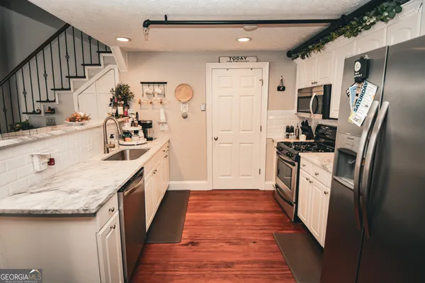 a kitchen with stainless steel appliances granite countertop a refrigerator a stove and a sink