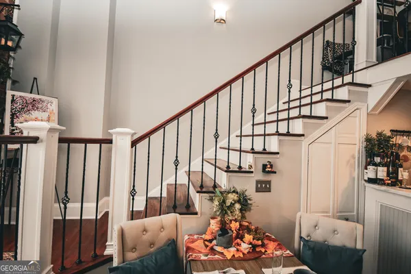 a living room with chairs stairs and a large window