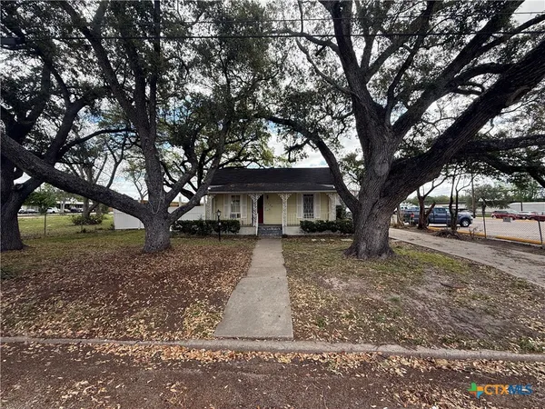 a white house that has a tree in front of the house