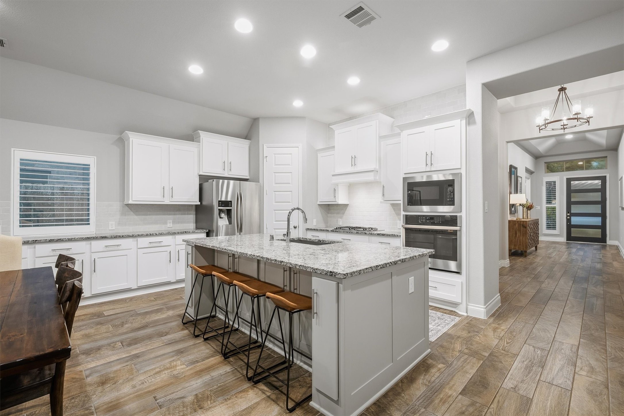 29118 Lantana Ridge Court Fulshear, TX 77441 - Photo 5 of 29 Fall in love with this beautifully designed kitchen featuring sleek white cabinets, a classic white subway tile backsplash, stainless steel appliances, and a spacious island that anchors the room—perfect for cooking, gathering, and entertaining in style.