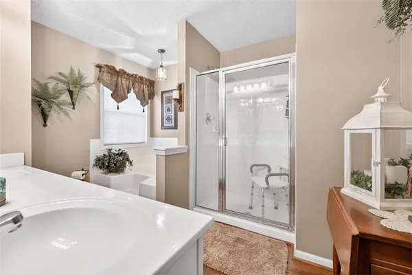 a spacious bathroom with a granite countertop sink a mirror a bathtub and shower