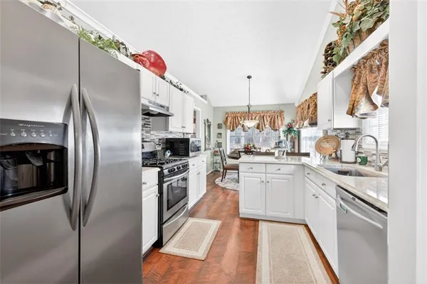 a kitchen with stainless steel appliances granite countertop a refrigerator a stove and a sink