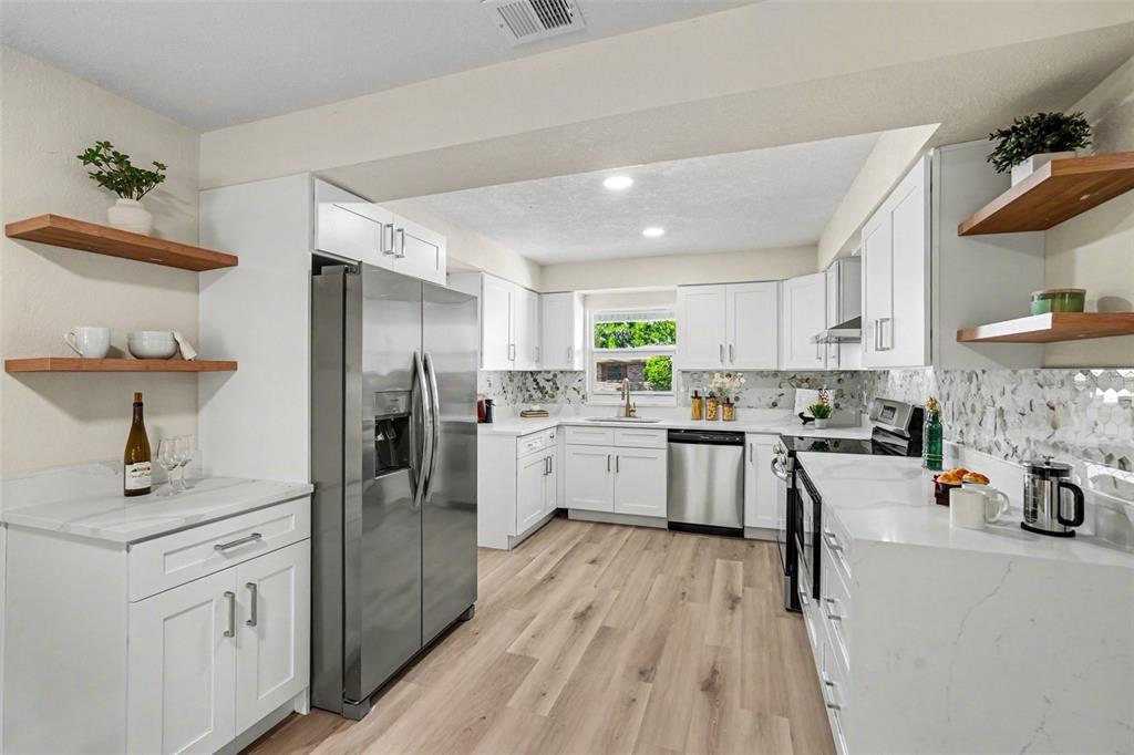 707 Queens Court Seffner, FL 33584 - Photo 14 of 28 a kitchen with white cabinets and stainless steel appliances