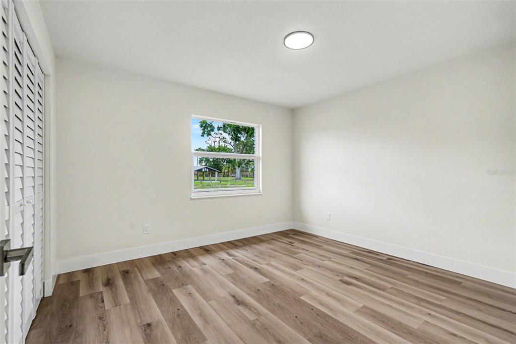 707 Queens Court Seffner, FL 33584 - Photo 17 of 28 an empty room with wooden floor and windows