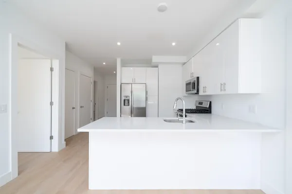 a kitchen with stainless steel appliances kitchen island a refrigerator sink and white cabinets
