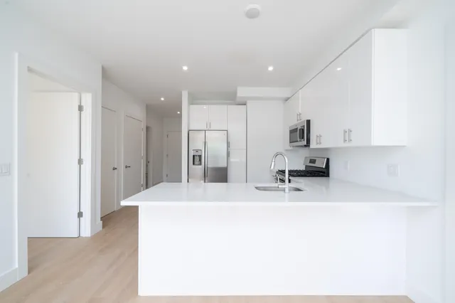 a kitchen with stainless steel appliances kitchen island a refrigerator sink and white cabinets
