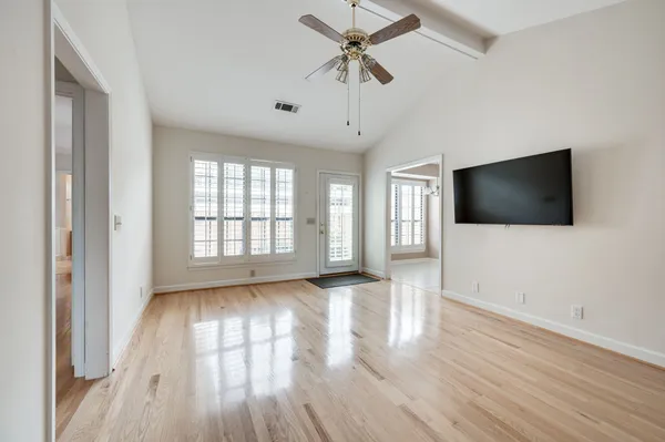 a view of a livingroom with wooden floor and a ceiling fan