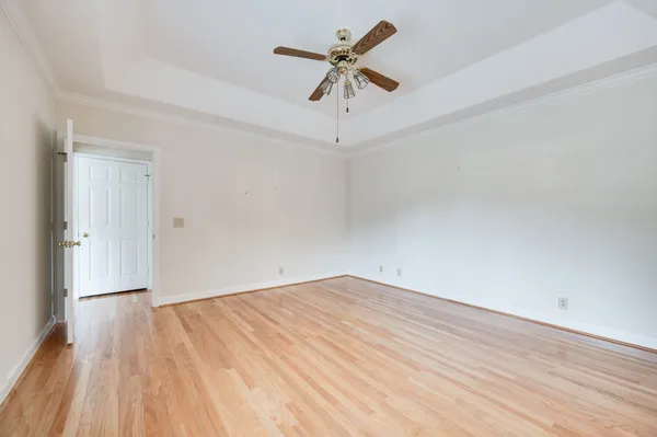 an empty room with wooden floor and ceiling fan