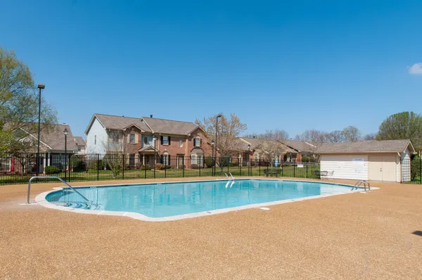 a view of a swimming pool and a yard in front of the house