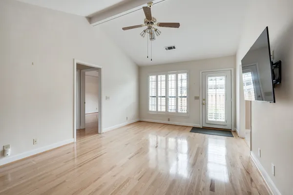a view of an empty room with a window and wooden floor