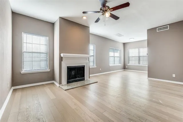 an empty room with windows fireplace and wooden floor