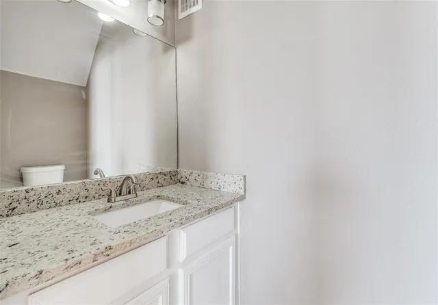 a bathroom with a granite countertop sink and a mirror