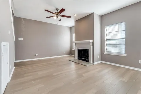 an empty room with ceiling fan and windows