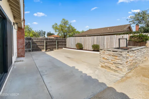 a backyard of a house with table and chairs and potted plants