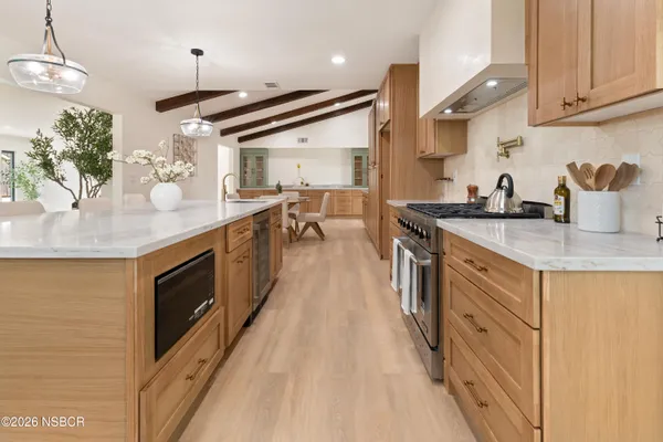 a kitchen with stainless steel appliances granite countertop a sink a stove and a wooden floors