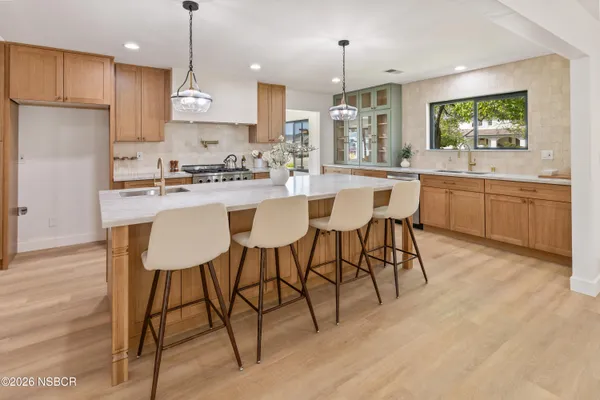 a kitchen with stainless steel appliances kitchen island granite countertop a sink a stove a dining table and chairs