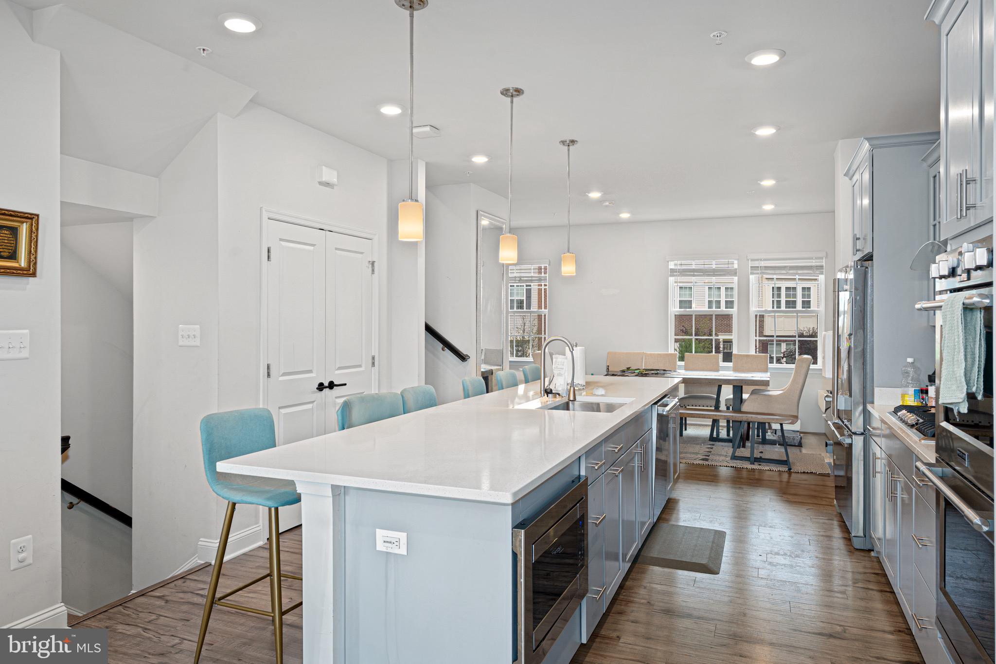 7583 Marston Way Hanover, MD 21076 - Photo 8 of 36 a kitchen with a stove a sink a kitchen island with chairs and white cabinets