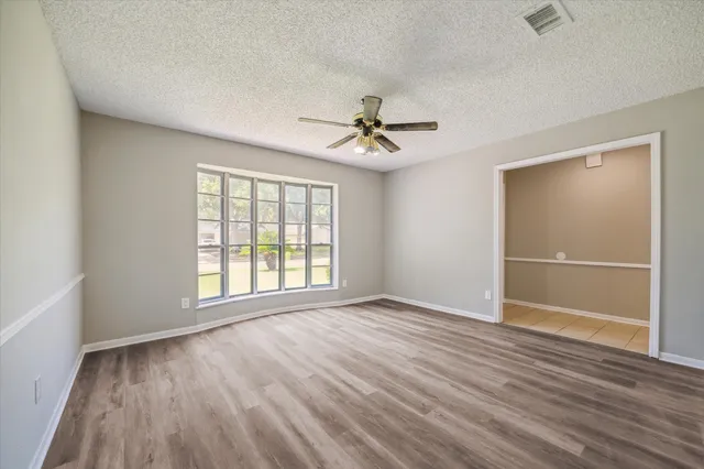 a view of an empty room with a window and wooden floor